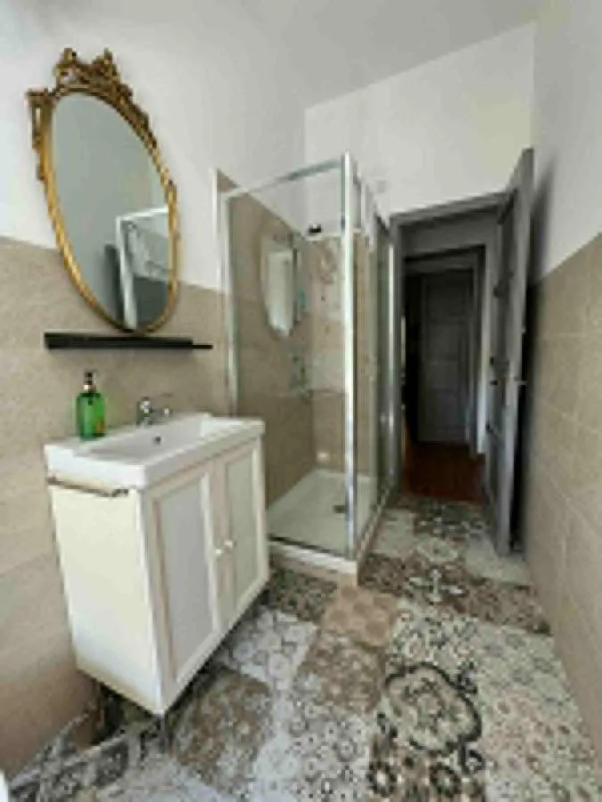 Il bagno privato con lo specchio ovale dorato, la doccia in vetro e le maioliche
