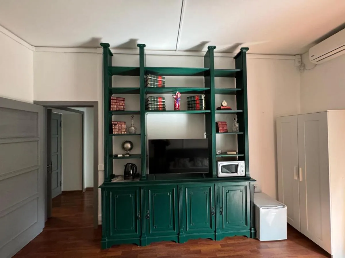 La libreria verde con la TV e l'armadio bianco